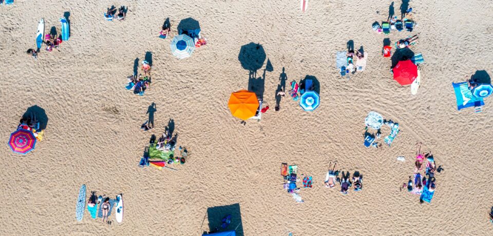 Top,Down,Aerial,View,Of,People,Relaxing,On,The,Sand Top view colored umbrellas on beach