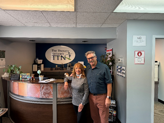man and woman standing in front of desk